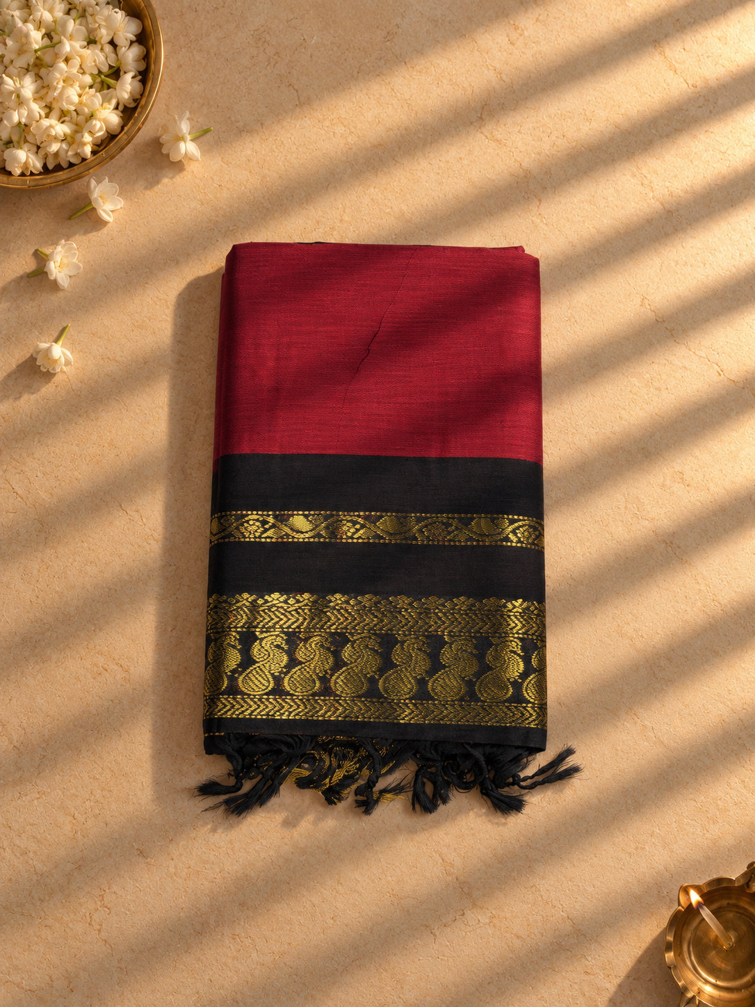 Maroon Gadwal cotton saree with black and gold zari border, folded